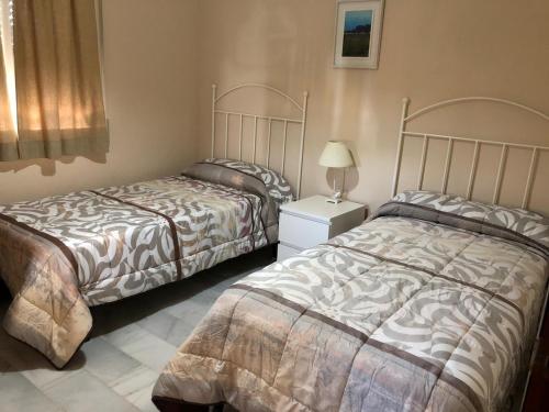 sypialnia z 2 łóżkami i stołem z lampką w obiekcie VILLA SALMONETE w mieście Sanlúcar de Barrameda