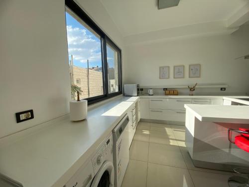 a kitchen with white cabinets and a window at Lemon Tree Residence in Amman