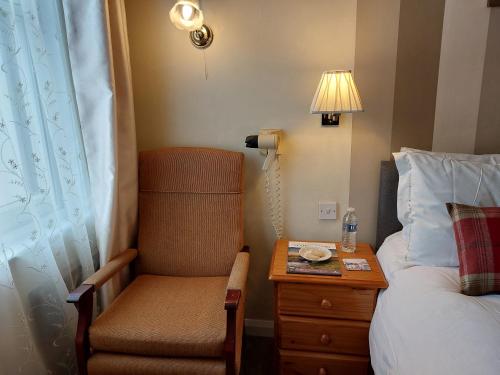 a bedroom with a chair and a table with a lamp at The Norwood in Torquay