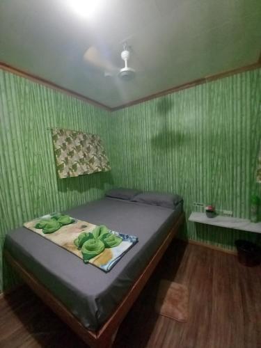 a bedroom with a bed with a green wall at Green Acres Village in Moalboal