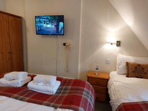 a bedroom with two beds and a tv on the wall at The Norwood in Torquay