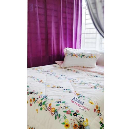 a bed with a white comforter with flowers on it at AdamPoolHomestay in Alor Setar