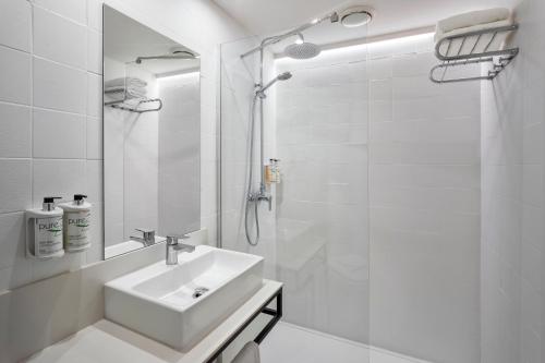 La salle de bains blanche est pourvue d'un lavabo et d'une douche. dans l'établissement B&B HOTEL Figueres, à Figueres