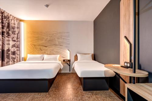 um quarto de hotel com duas camas e uma mesa em B&B HOTEL Bois d'Arcy Saint Quentin en Yvelines em Bois-dʼArcy