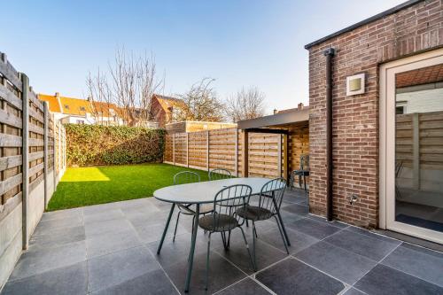 a patio with a table and chairs in a backyard at Holidayhouse Kongé, a place that you call home! in Bruges