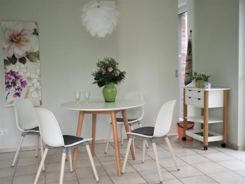 a white table with chairs and a vase with flowers at Schickes Wohnstudio mit Garten am Aasee in Ibbenbüren