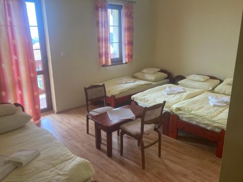 a room with four beds and a table and chairs at Bazilika Vendégház in Tarcal