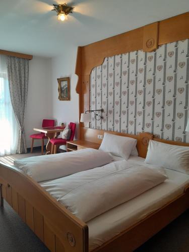Schlafzimmer mit einem großen Bett mit einem Kopfteil aus Holz in der Unterkunft Gästehaus Zunterer in Wallgau