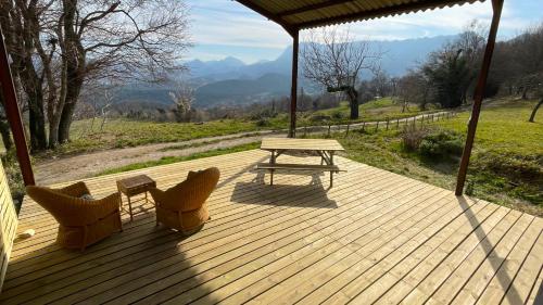 a wooden deck with a picnic table and two chairs at Gîtes du Puyjovent - Côté Vallée - à 15 minutes de Crest, vue panoramique, calme in Piégros-la-Clastre