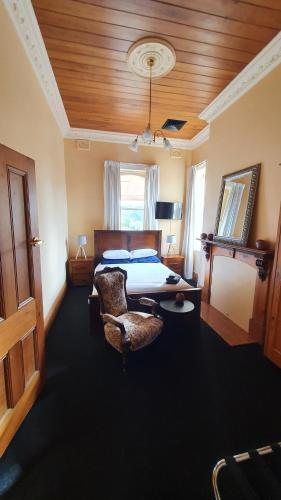 ein Schlafzimmer mit einem Bett und einem Stuhl in einem Zimmer in der Unterkunft Mendrinas at Brooklyn in Tumut