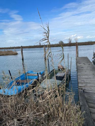 a boat sitting on the water next to a dock at Appartamento Lavanda - Casa vacanza nel Delta del Po in Ca Zuliani