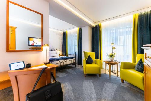 a hotel room with a desk and yellow chairs at Hotel BEI SCHUMANN in Kirschau