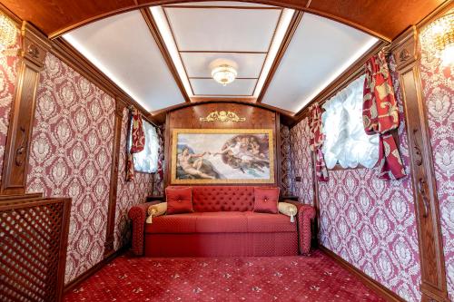 un vagón de tren con un sofá rojo en una habitación en Хотел Глемпинг Алианс en Plovdiv