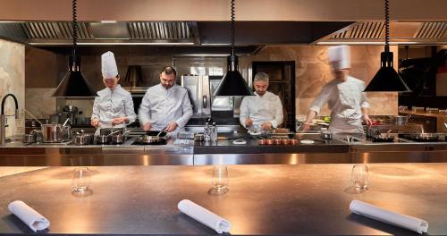 a group of chefs preparing food in a kitchen at The Glamore Milano Duomo in Milan