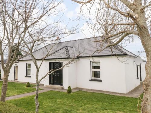 a white house with trees in front of it at Old Head View in Louisburgh