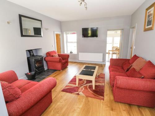 a living room with two red couches and a fireplace at Old Head View in Louisburgh