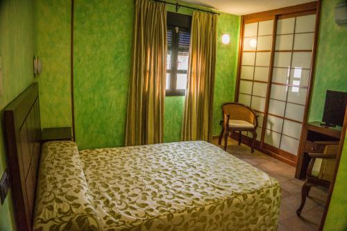 um quarto com uma cama, uma cadeira e uma janela em El Soportal de Uceda em Uceda