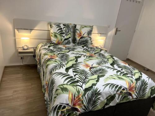 a bedroom with a bed with a bedspread with palm leaves at Entre mer et Montagne in Prades