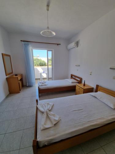 a bedroom with two beds and a large window at White rose in Kámpos