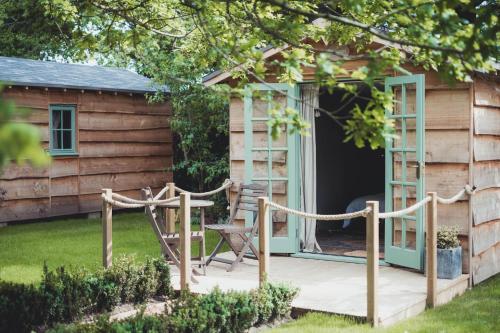 drewniany domek z werandą i krzesłem w obiekcie Toad Hall Lodges - Luxury Eco Lodges Near Southwold! w mieście Wangford