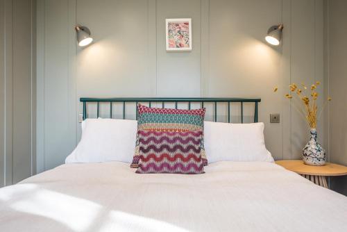 a bed with a colorful pillow on top of it at Toad Hall Lodges - Luxury Eco Lodges Near Southwold! in Wangford