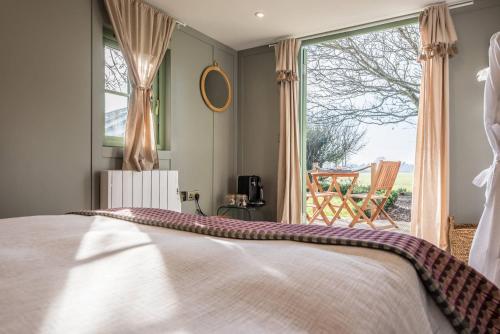 a bedroom with a bed and a large window at Toad Hall Lodges - Luxury Glamping Lodges Near Southwold! in Wangford