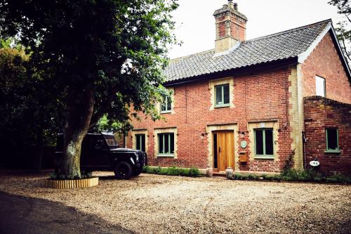 a truck parked in front of a brick building with a tree at Toad Hall Lodges - Luxury Glamping Lodges Near Southwold! in Wangford