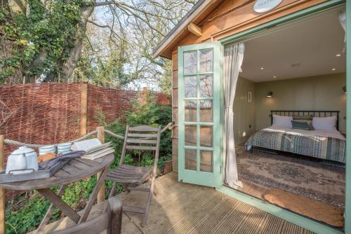 a patio with a bed and a table and chairs at Toad Hall Lodges - Luxury Glamping Lodges Near Southwold! in Wangford