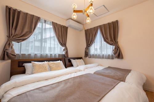 two beds in a bedroom with two windows at Y's沖縄リゾートベースNo.2 in Onna