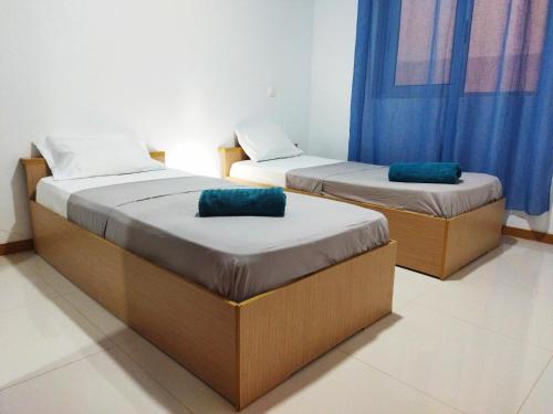 two beds in a room with blue curtains at Apto Morabeza T2 Praia in Praia
