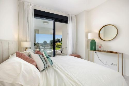 1 dormitorio con cama blanca y ventana grande en Luxury 2bed apartment Mirador del Golf, Estepona, en Estepona