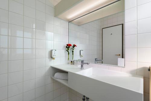a white bathroom with a sink and a mirror at Wyndham Garden Donaueschingen in Donaueschingen