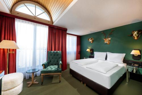 a bedroom with a white bed and a green wall at Wyndham Garden Donaueschingen in Donaueschingen