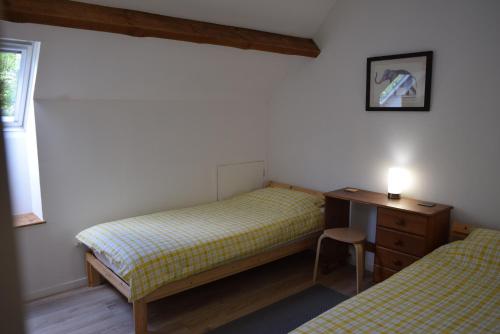 a bedroom with two beds and a desk and a window at Appartement Privé, Camping La Pointe in Châteaulin