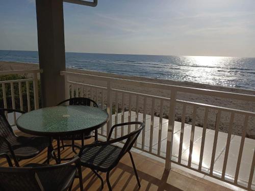 een tafel en stoelen op een balkon met uitzicht op het strand bij CASA DE LEON Private Beach House in Candon