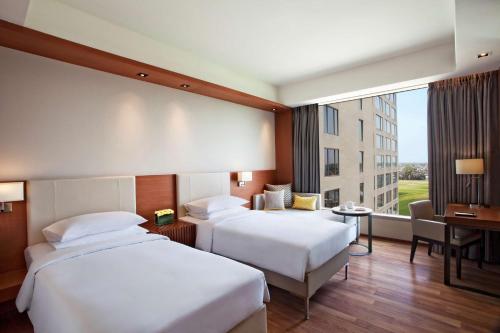 ein Hotelzimmer mit 2 Betten, einem Schreibtisch und einem Fenster in der Unterkunft Hyatt Regency Amritsar in Amritsar