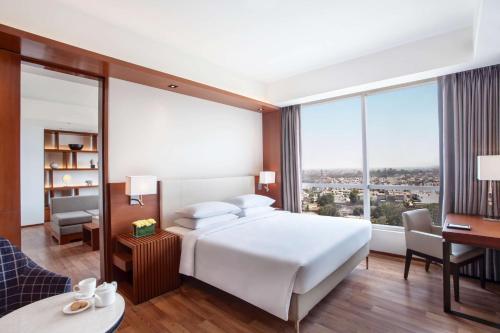 a bedroom with a large white bed and a desk at Hyatt Regency Amritsar Hotel & Spa in Amritsar