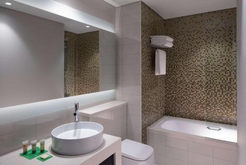 a bathroom with a sink and a tub and a toilet at Hyatt Place Dubai Jumeirah in Dubai