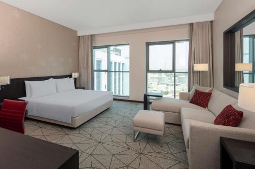 Hyatt Place Dubai Jumeirah في دبي: غرفه فندقيه بسرير واريكه