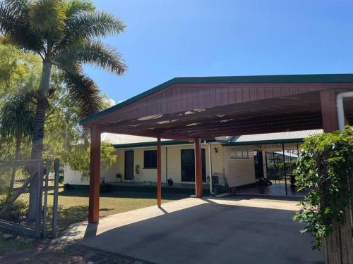 um edifício com uma palmeira em frente em Cosy Queenslander in the heart of town. em Mareeba