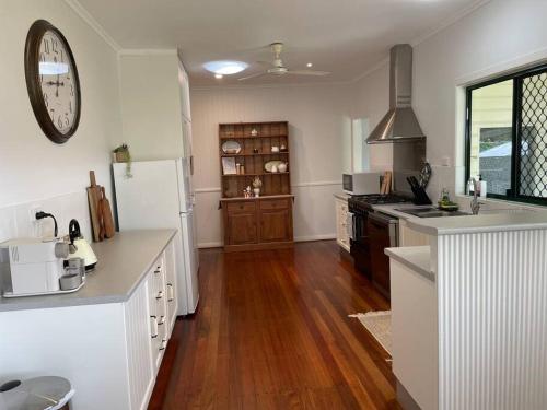 uma cozinha com electrodomésticos brancos e piso em madeira em Cosy Queenslander in the heart of town. em Mareeba