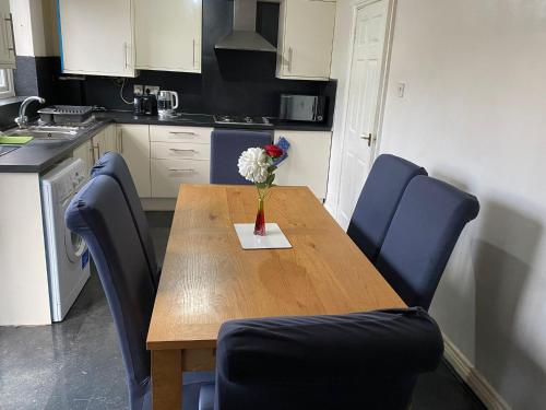 cocina con mesa de madera y sillas azules en budget private rooms close to city centre and airport, en Birmingham