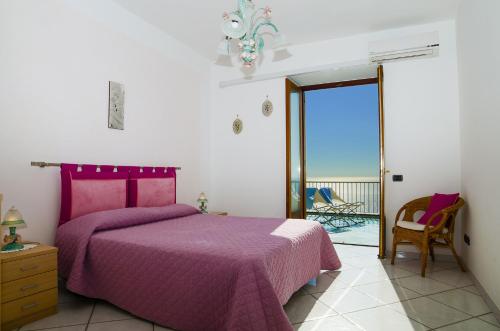 una camera con letto viola e balcone di Moressa a Praiano