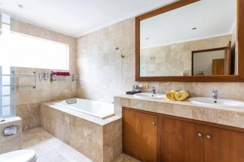 a bathroom with two sinks and a tub and a mirror at White Moon - Dream 5br Villa in Legian close to the Beach in Kuta