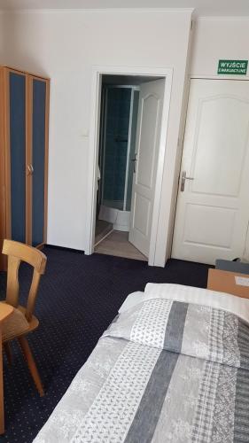 a bedroom with a bed and a chair and a door at Hotel Alicja in Łódź
