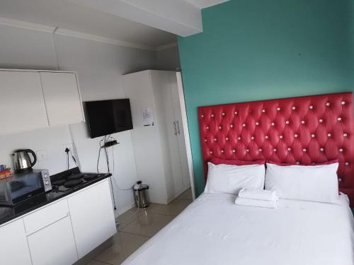 a bed with a red headboard in a room at Modern Oxford Street Apartment - 40 CZ KUBS in East London