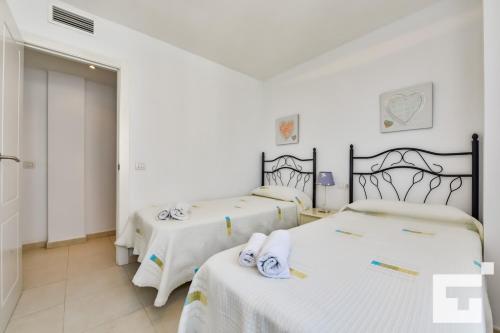 two beds in a white room with towels on them at Apartamento Apolo XIX 34L - Grupo Turis in Calpe