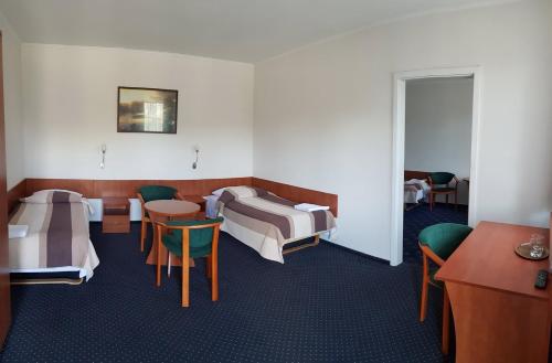 Cette chambre comprend deux lits, une table et des chaises. dans l'établissement Hotel Alicja, à Łódź