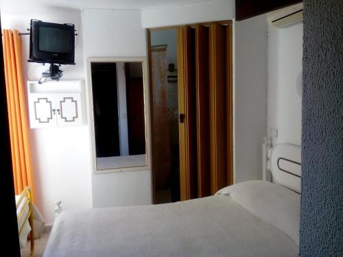 a bedroom with a bed and a tv on the wall at Residência Matos Pereira in Vila Real de Santo António
