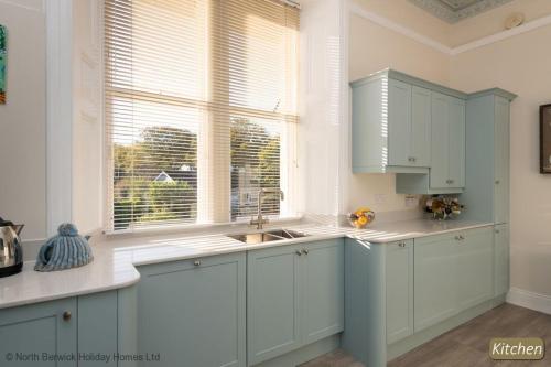 a kitchen with white cabinets and a sink and a window at Seascape in North Berwick